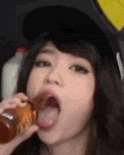 a woman is drinking from a bottle with her tongue sticking out .