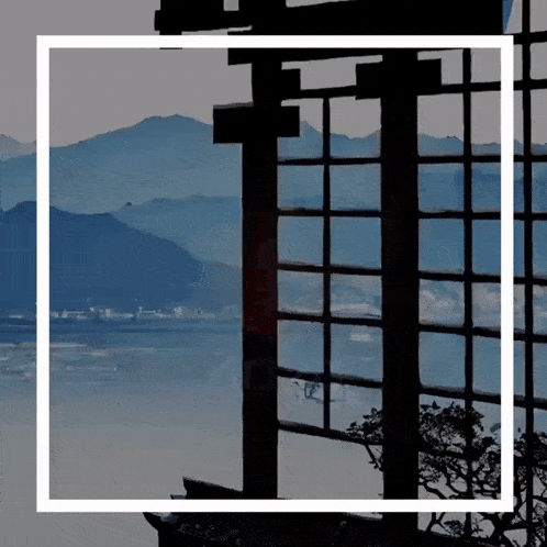 a window with a view of a body of water and mountains in the background