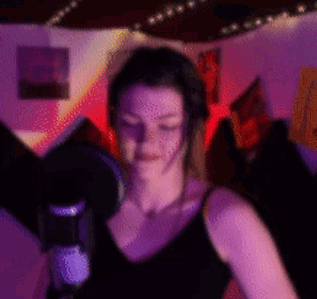 a blurry picture of a woman in front of a microphone with purple lights behind her