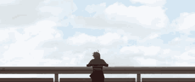 a silhouette of a person standing on a railing looking at the clouds