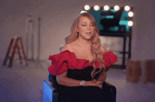 a woman in a red off the shoulder top is sitting in front of a mirror
