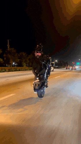 a person is riding a motorcycle on a highway at night with a helmet that says ' biker ' on it