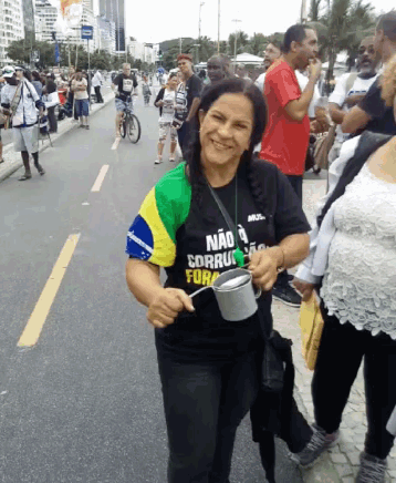 a woman wearing a black shirt that says " não corrupto fora " holds a bucket