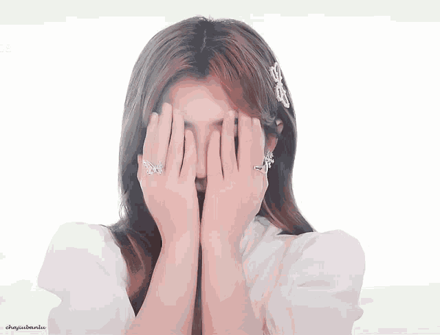 a woman covering her face with her hands and a butterfly ring on her finger