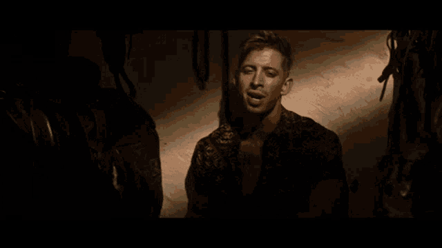 a man in a shirt is standing in a dark room with his mouth open