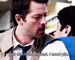a man in a suit and tie is talking to another man in a blue vest .