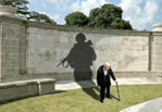 an elderly man with a cane stands in front of a wall with a shadow of a soldier on it