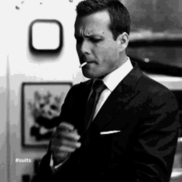a man in a suit is smoking a cigarette in a black and white photo