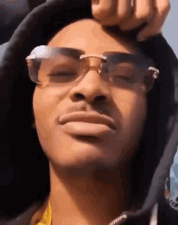 a close up of a person wearing sunglasses and a hood .