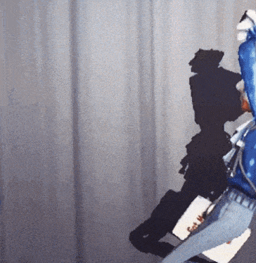 a person in a blue jacket is standing in front of a curtain