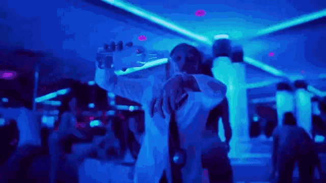 a man is taking a selfie with a cell phone in a dark room with blue lights .