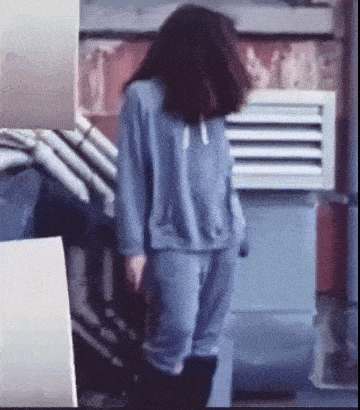 a woman wearing a blue sweatshirt and pants is standing in a room