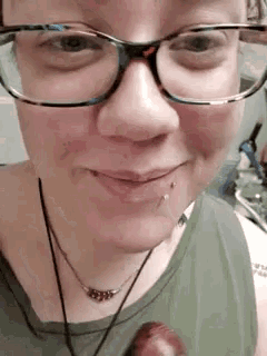 a woman wearing glasses and a green tank top is smiling .