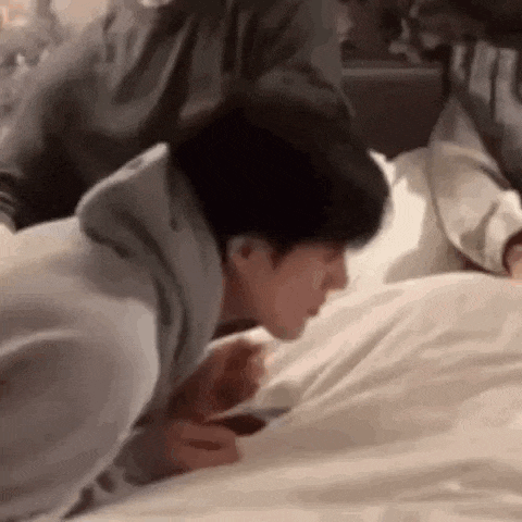a man is laying on a bed with his head on a pillow .