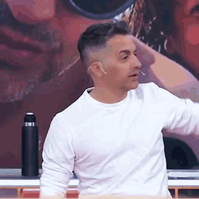a man in a white shirt is standing in front of a painting of a man and woman .