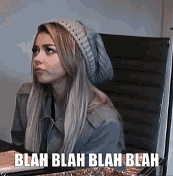 a woman wearing a beanie sits in a chair with the words blah blah blah blah