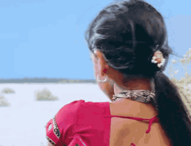 a woman in a red top is looking out over a lake