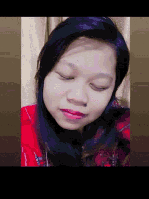 a woman with her eyes closed wearing a red jacket