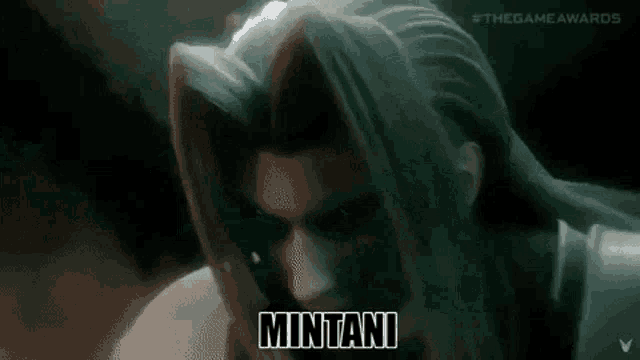 a man with long hair and a beard is making a funny face and says mintani .
