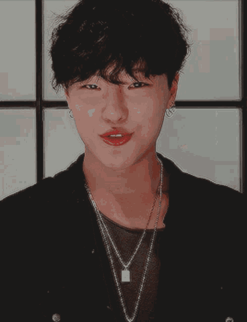 a young man wearing a black jacket and a necklace
