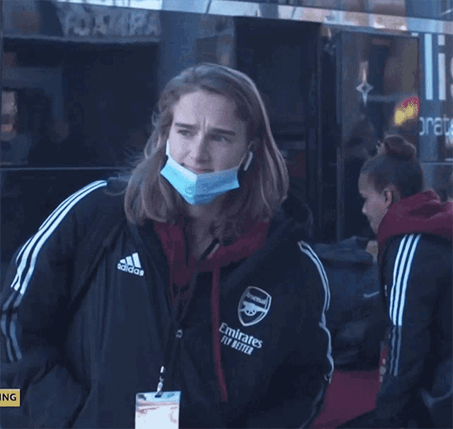 a woman wearing a mask and an adidas jacket