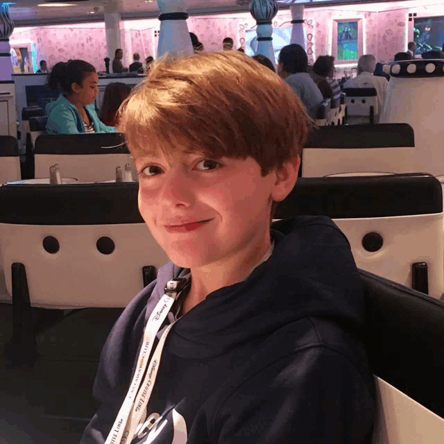 a young boy wearing a lanyard that says ' disney cruise ' on it