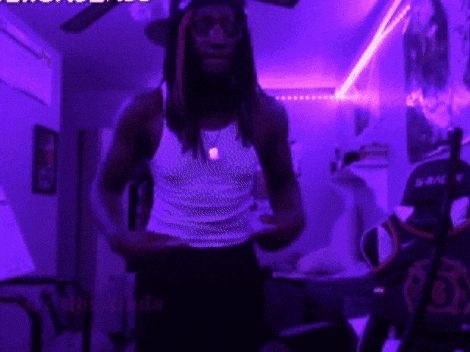a man in a white tank top is standing in front of a purple wall