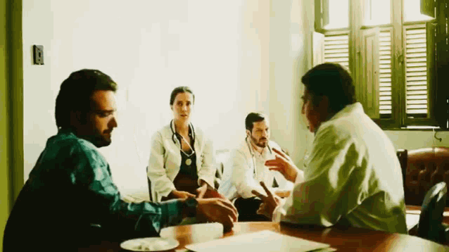 a group of people are sitting around a table and talking to each other