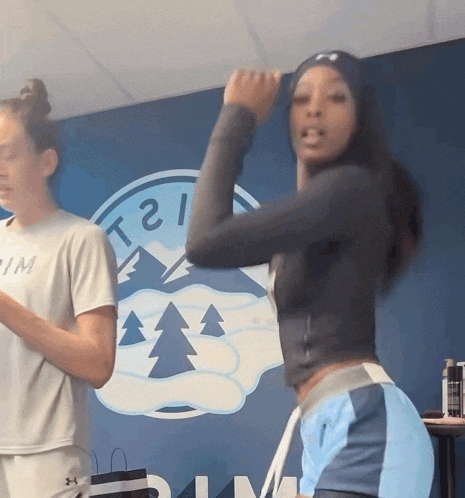 two women are dancing in front of a sign that says ' t21 '