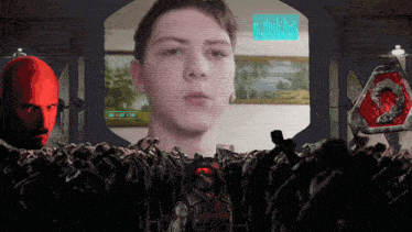 a man 's face is displayed on a screen surrounded by zombies and a red head