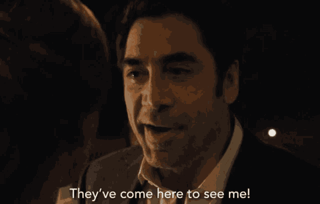 a man in a suit is talking to a woman and they 've come here to see me