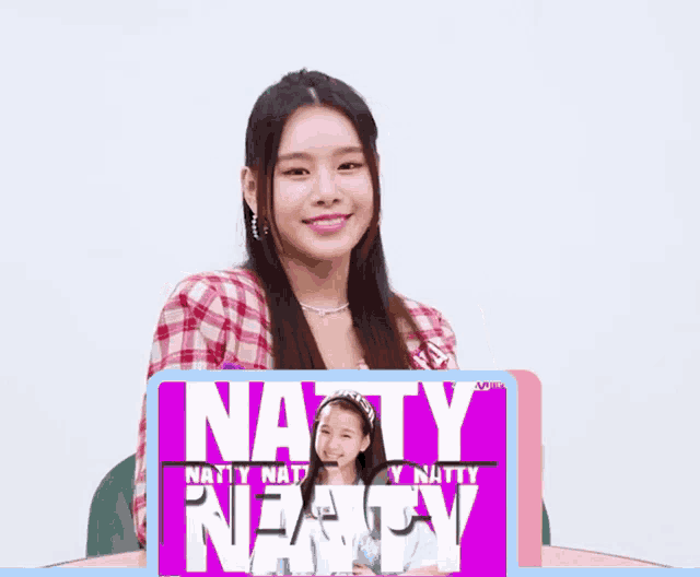 a girl in a plaid shirt is holding a sign that says natty nexty