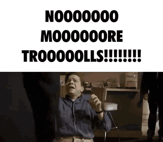 a man in a blue shirt is standing in front of a sign that says noo00000 moooooore trooooolls !!!