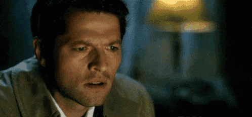 a close up of a man 's face with a surprised look on his face in front of a lamp .