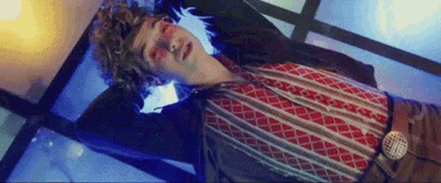 a man with curly hair is laying on a bed