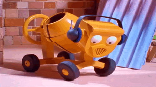 a yellow toy cement mixer wearing headphones is sitting in front of a brick wall