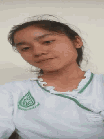 a young girl wearing a white shirt with a green logo on the front