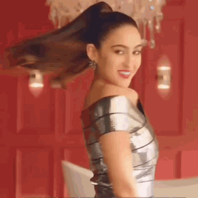 a woman is wearing a silver dress and a ponytail .