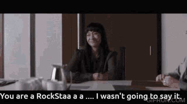 a woman sitting at a table with the words you are a rockstaa a a i wasn t going to say