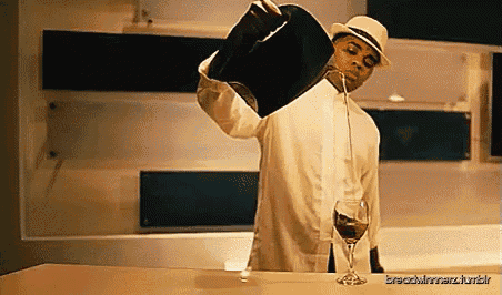 a man is pouring a glass of wine from a black bucket