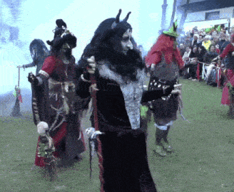 a group of people dressed up as witches are standing in the grass