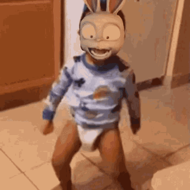 a baby wearing a diaper and a bunny mask is dancing on a tiled floor .