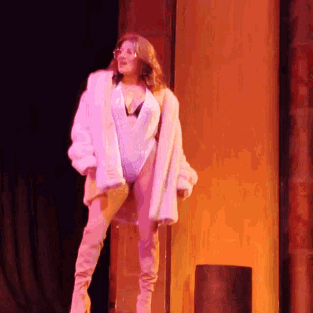 a woman in a fur coat and thigh high boots is standing on a stage