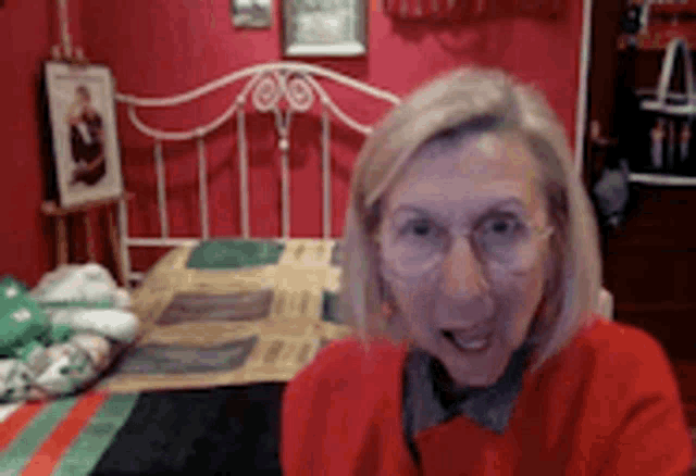 a woman wearing glasses is sitting in front of a bed