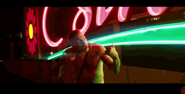 a man is standing in front of a neon sign that says " love "