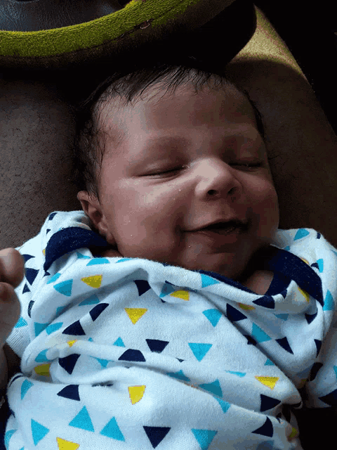 a baby wearing a blue yellow and white triangle blanket