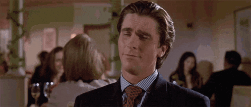 a man in a suit and tie is making a face with his hands in a crowded room .