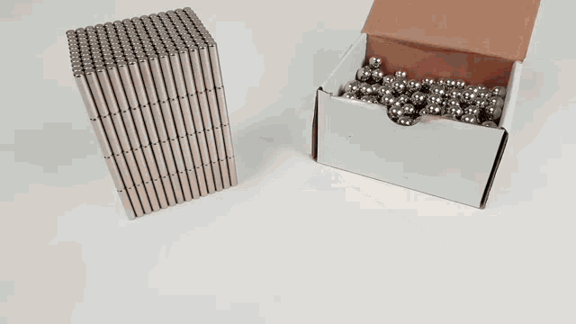 a box of metal balls next to a stack of metal sticks