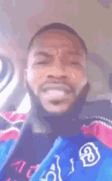 a man with a beard is wearing a blue and pink jacket with the letter a on it