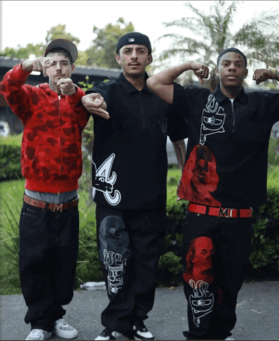 three men are posing for a picture with one wearing a black shirt with a dollar sign on it